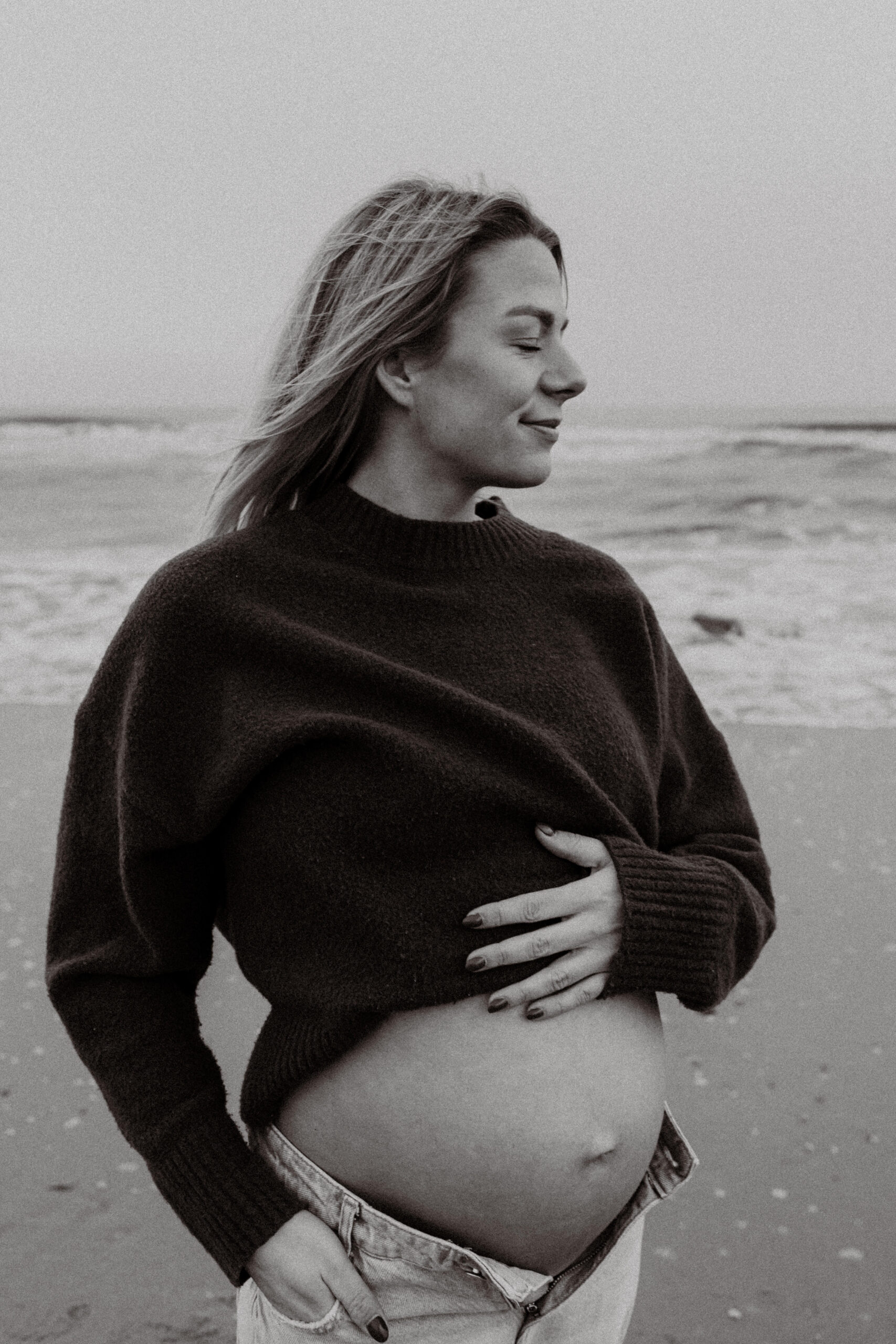 Zwangerschapsshoot strand Katwijk, ogen dicht, hand op de buik