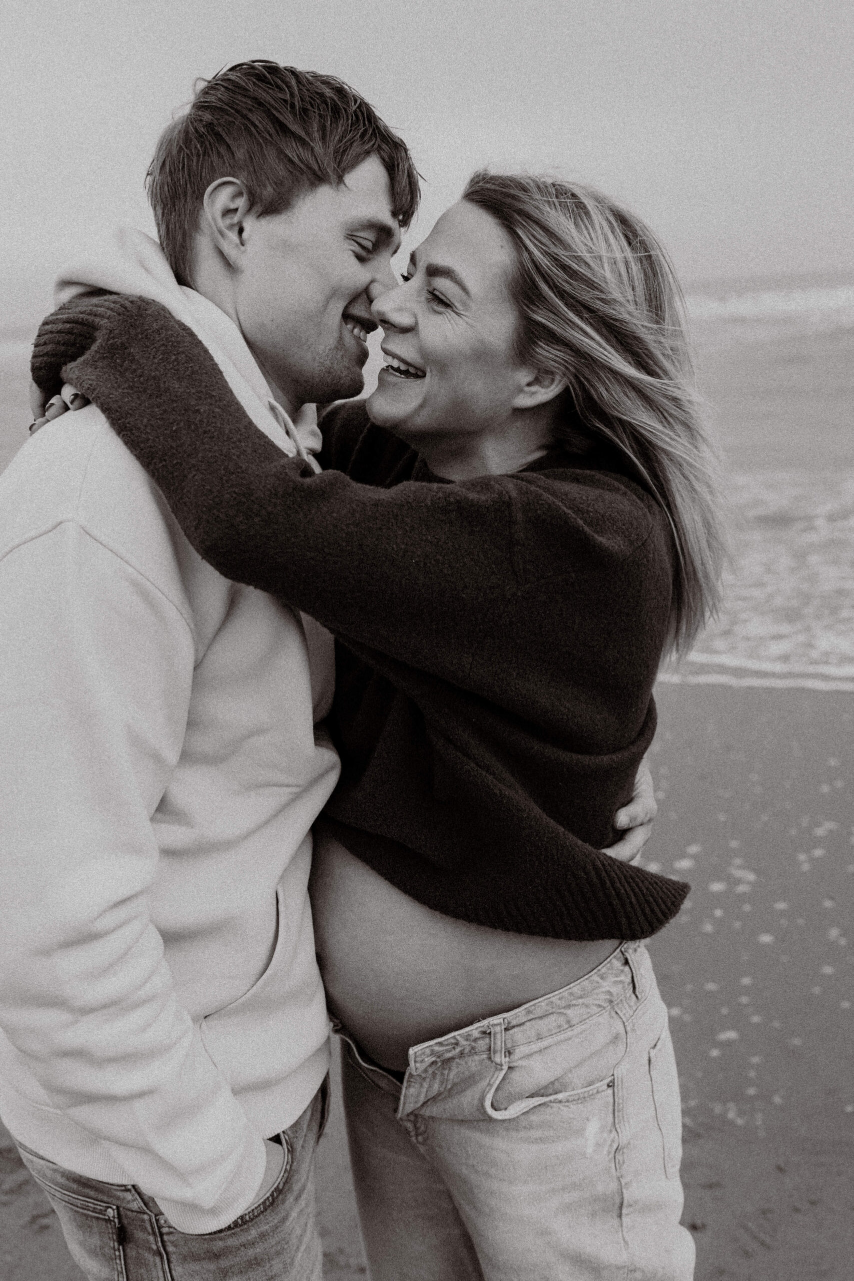 Zwangerschapsshoot op het strand in Katwijk, omarmen elkaar