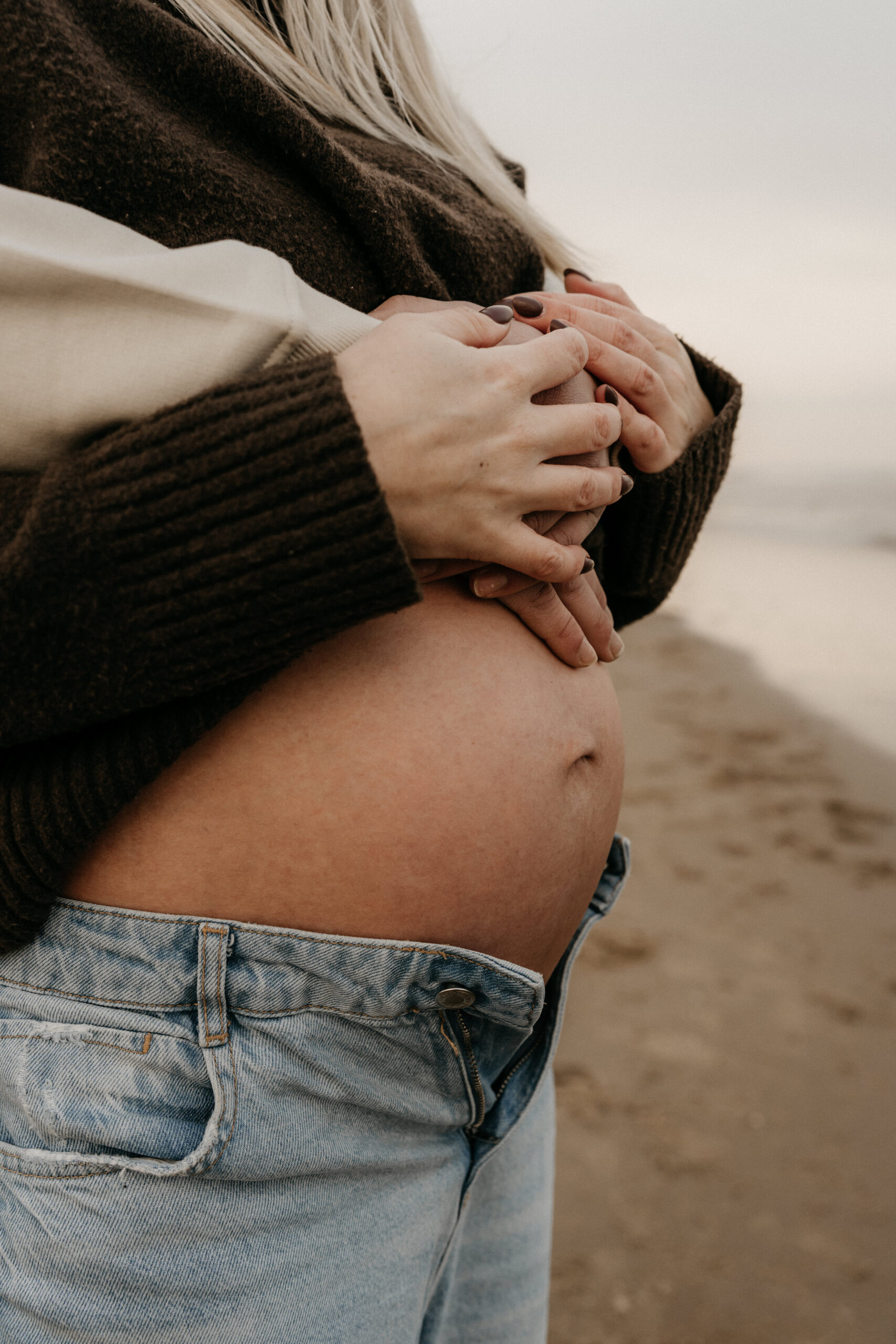 Zwangerschapsshoot strand Katwijk, handen op de buik